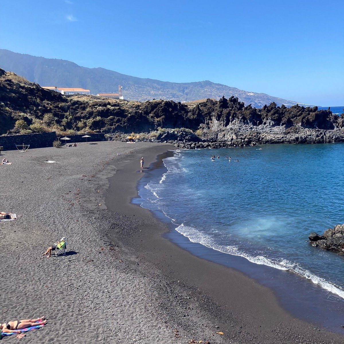 the black volcanic sand beach at Los Cancajos with its stone breakwaters forming calm coves
